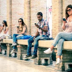 Group of young multiracial friends using smartphone with mutual disinterest towards each other - Technology addiction in actual lifestyle - Soft vintage filtered look with main focus on male person